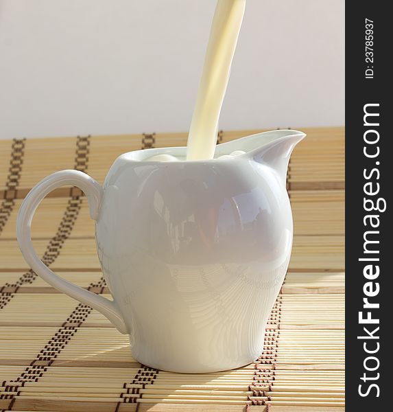 Pouring milk into white ceramic milk jug