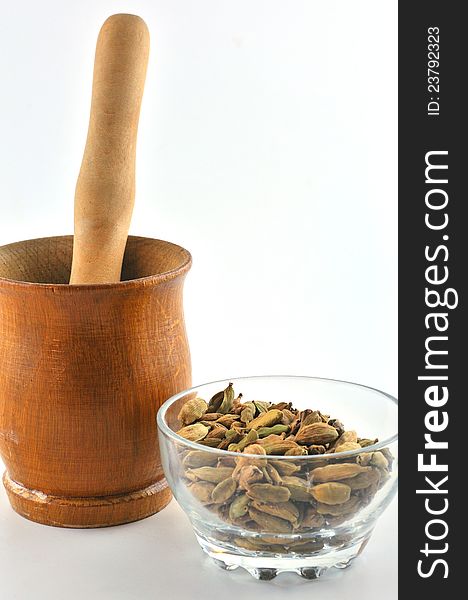 Cardamom seeds in a glass bowl and a number of wooden mortar for grinding the seeds into a powder