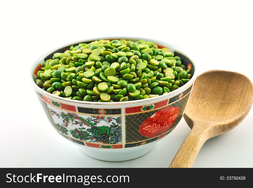 Ceramic bowl decorated with a color full of dry beans and peas next to a wooden spoon. Ceramic bowl decorated with a color full of dry beans and peas next to a wooden spoon