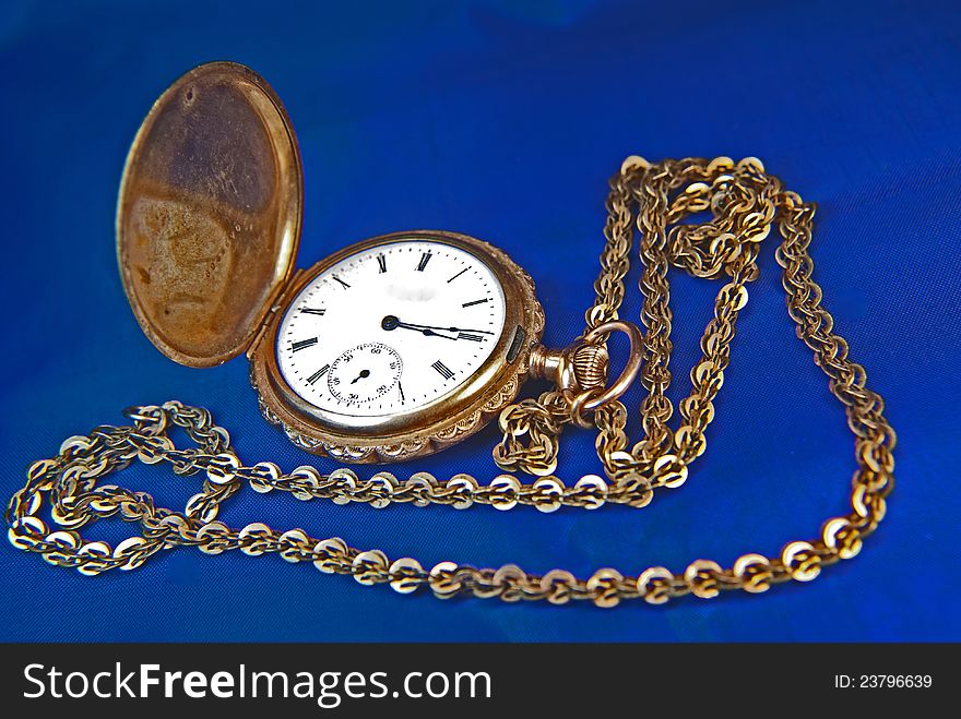 Antique pocket-watch with chain on blue