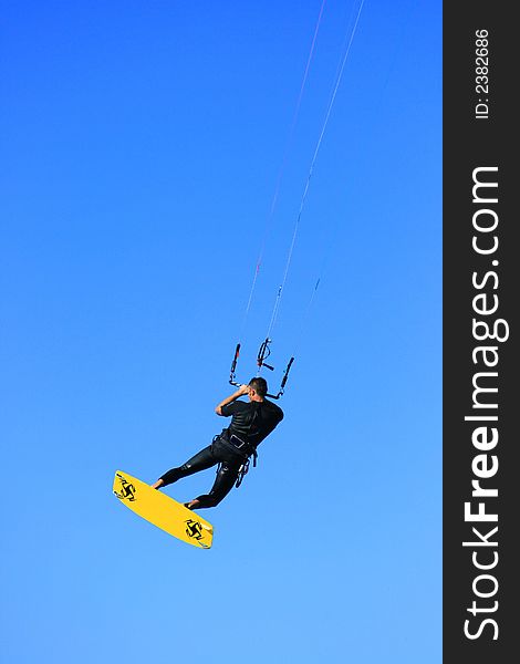 A kitesurfer in midair on blue background. A kitesurfer in midair on blue background
