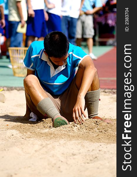 A Boy sitting on the sands field after long jump. A Boy sitting on the sands field after long jump.