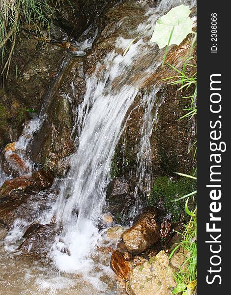 Water flowing between rocks and flowers in summer. Water flowing between rocks and flowers in summer