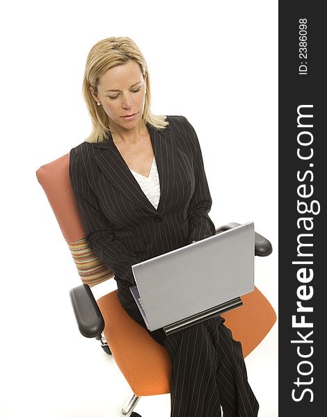 A businesswoman in a pinstripe suit sits relaxing in a chair with a laptop computer. A businesswoman in a pinstripe suit sits relaxing in a chair with a laptop computer