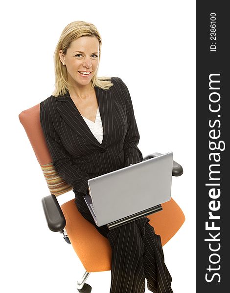 A businesswoman in a pinstripe suit sits relaxing in a chair with a laptop computer and smiles. A businesswoman in a pinstripe suit sits relaxing in a chair with a laptop computer and smiles