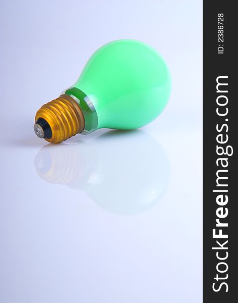 A green lightbulb over white with reflection