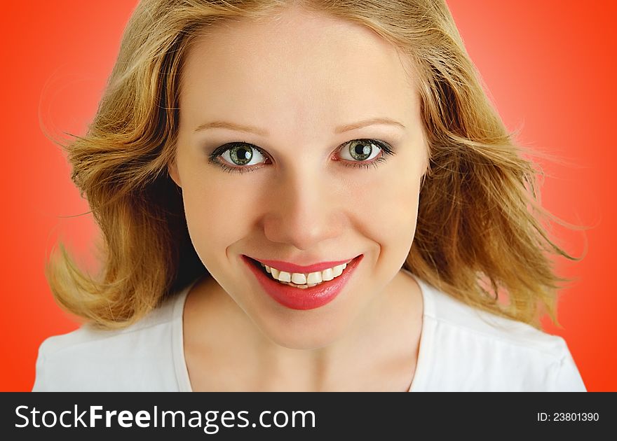 Smiling face of a beautiful girl with flowing hair close up on a red background. Smiling face of a beautiful girl with flowing hair close up on a red background