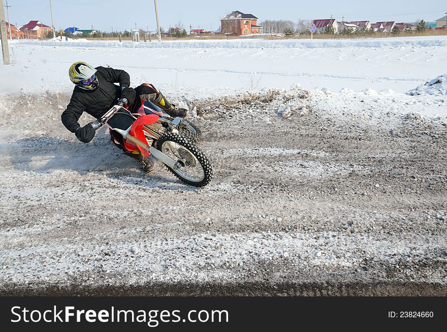 Winter motocross, rider turns the with the slope of the motorcycle and skidding on snowy highway. Winter motocross, rider turns the with the slope of the motorcycle and skidding on snowy highway