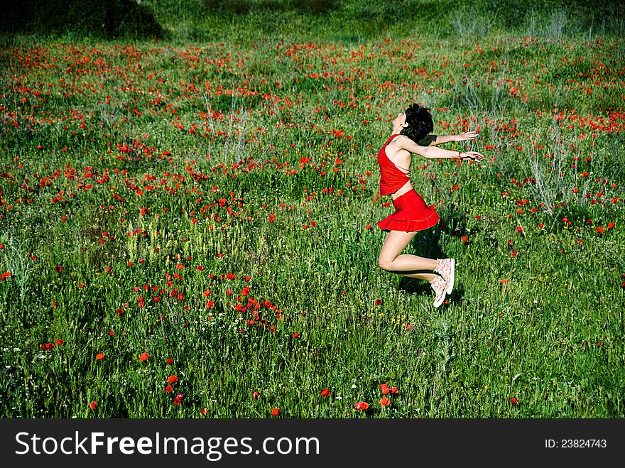 Happy woman jumping in poppy field