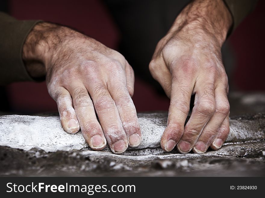 Two rough and dirty hands grip a rock ledge during a bouldering outing. Hands are covered in chalk and grit. Two rough and dirty hands grip a rock ledge during a bouldering outing. Hands are covered in chalk and grit.