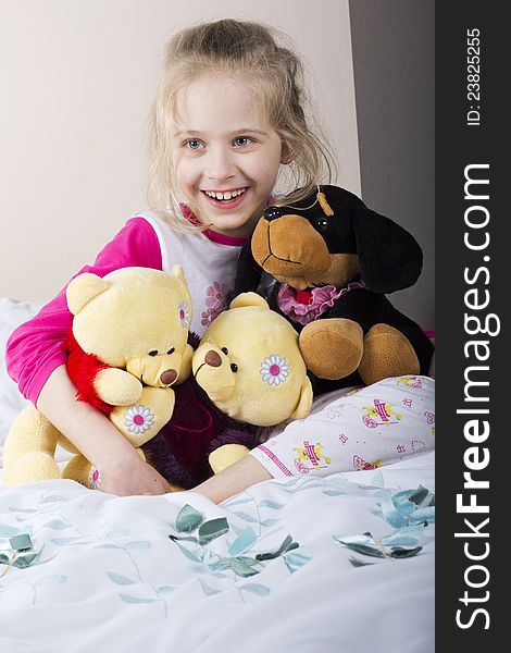 Young girl in bed holding her toys. Young girl in bed holding her toys
