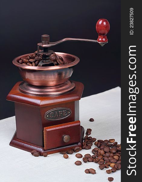 Nice vintage manual coffee grinder near beans on canvas background. Nice vintage manual coffee grinder near beans on canvas background