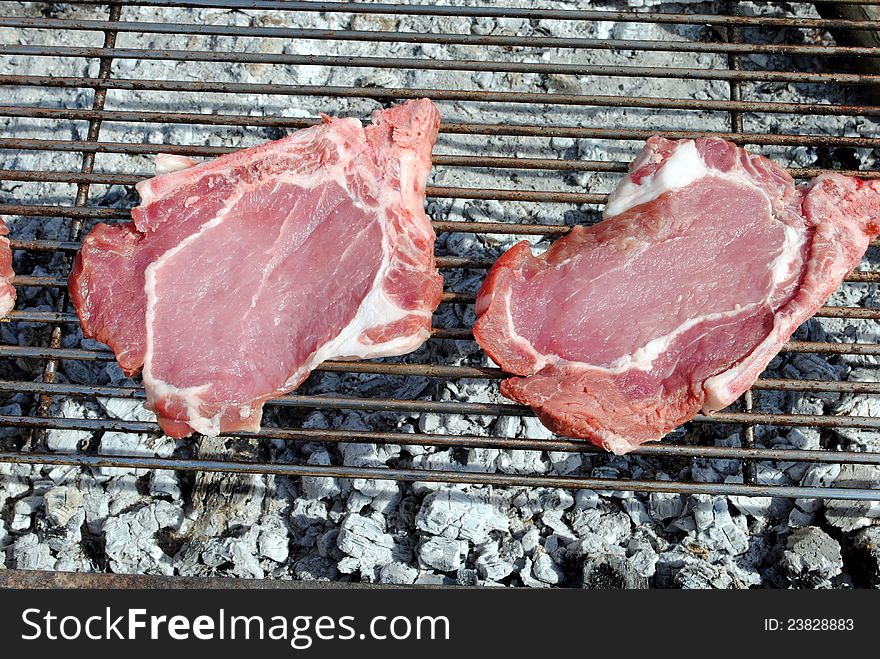 Raw pork chops grill on a barbecue