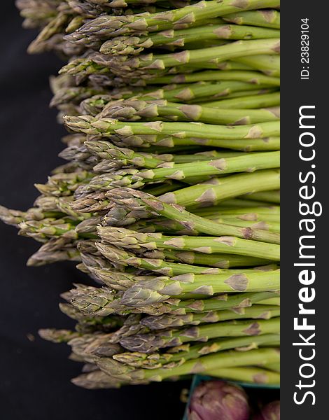 Freshly harvested organic asparagus spears with baskets purple artichokes