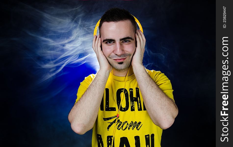 Smiling young man listening to the music through yellow headphones. Smiling young man listening to the music through yellow headphones