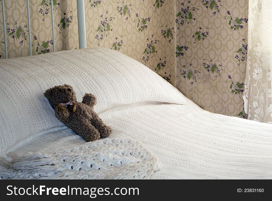 Old fashioned toy teddy bathed in window light on an old iron bed. Old fashioned toy teddy bathed in window light on an old iron bed