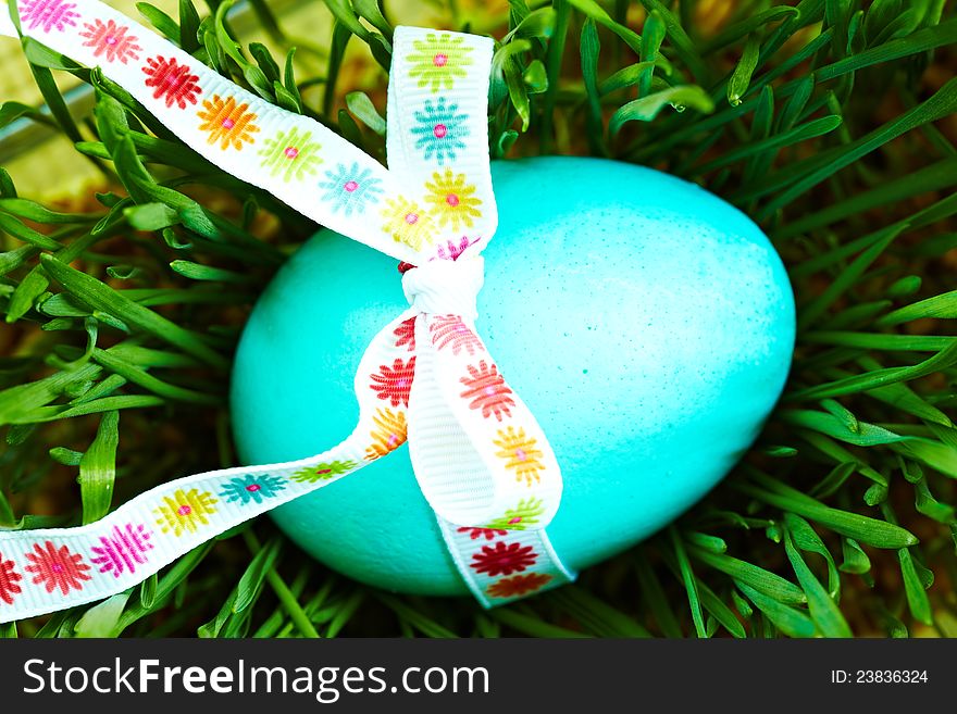 Easter egg with ribbon on the grass.