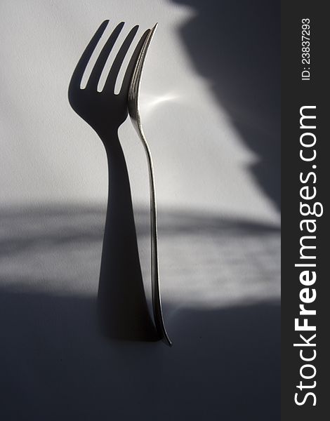 Silver fork on light background with shadows. Silver fork on light background with shadows