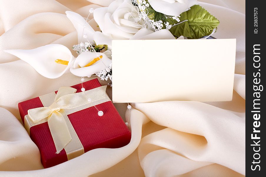 Holiday gift with a bouquet of the bride and a card on a gentle silk