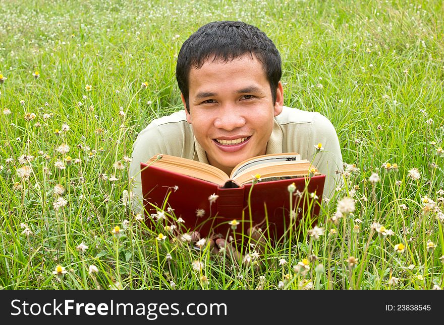 Asian man reading on the field