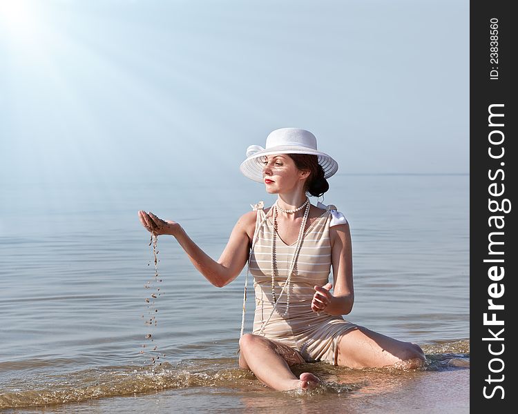 Woman in white hat posing against the sea