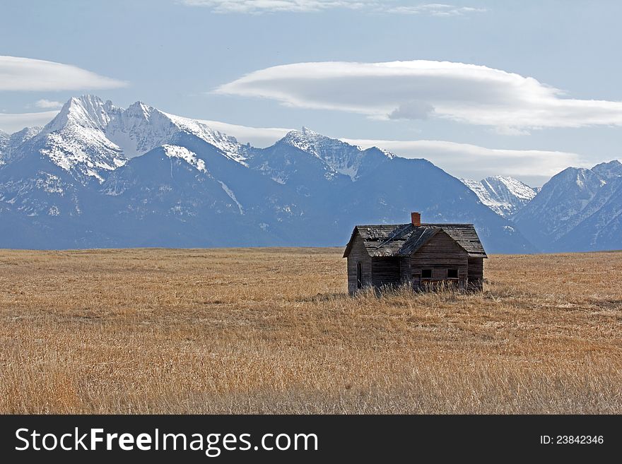 This image of the old, but still standing, abandoned home on the prairie with the snow covered mountains in the background was taken in Ronan, MT. This image of the old, but still standing, abandoned home on the prairie with the snow covered mountains in the background was taken in Ronan, MT.