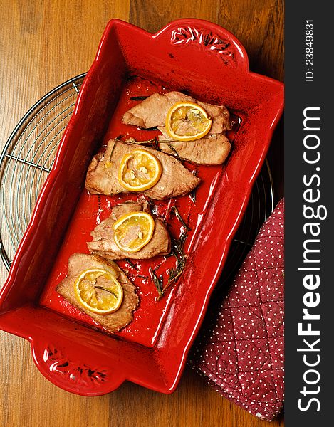 Roasted turkey pieces with lemon slices and rosemary in a red ceramic pot. Roasted turkey pieces with lemon slices and rosemary in a red ceramic pot