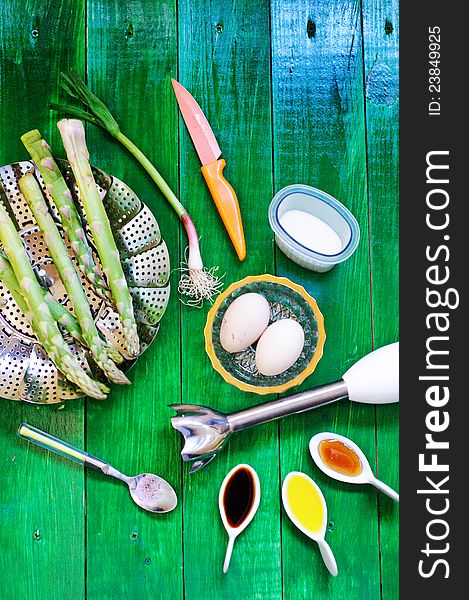 Asparagus soup ingredients and kitchen wear on a green table. Asparagus soup ingredients and kitchen wear on a green table