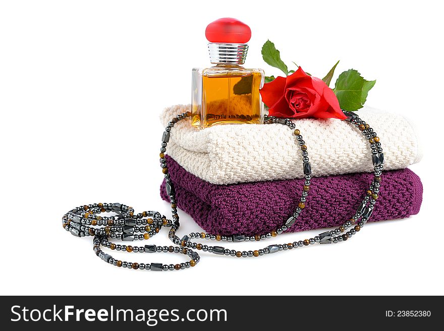Perfume bottle,red rose  and beads with stacked towels on white background. Perfume bottle,red rose  and beads with stacked towels on white background