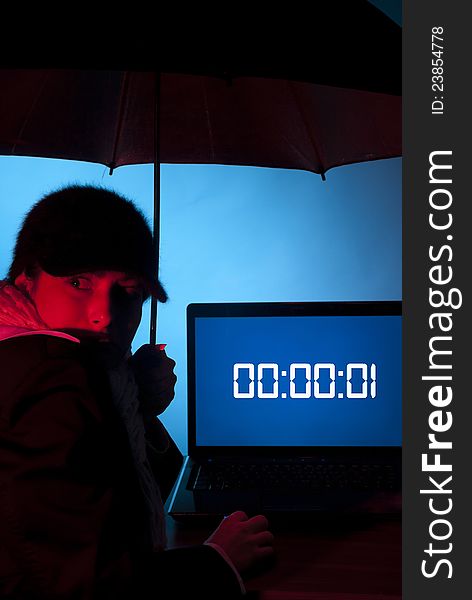 Woman with an umbrella looking fearful with a laptop in front of her with the time that has expired waiting for a dangerous rain. Woman with an umbrella looking fearful with a laptop in front of her with the time that has expired waiting for a dangerous rain