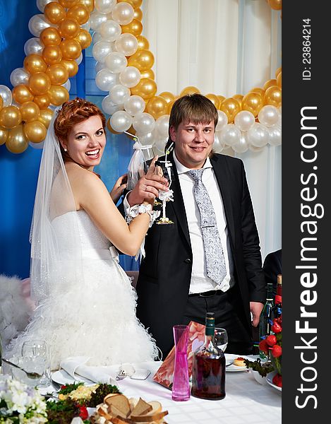 Happy bride and groom with champagne glasse in banquet