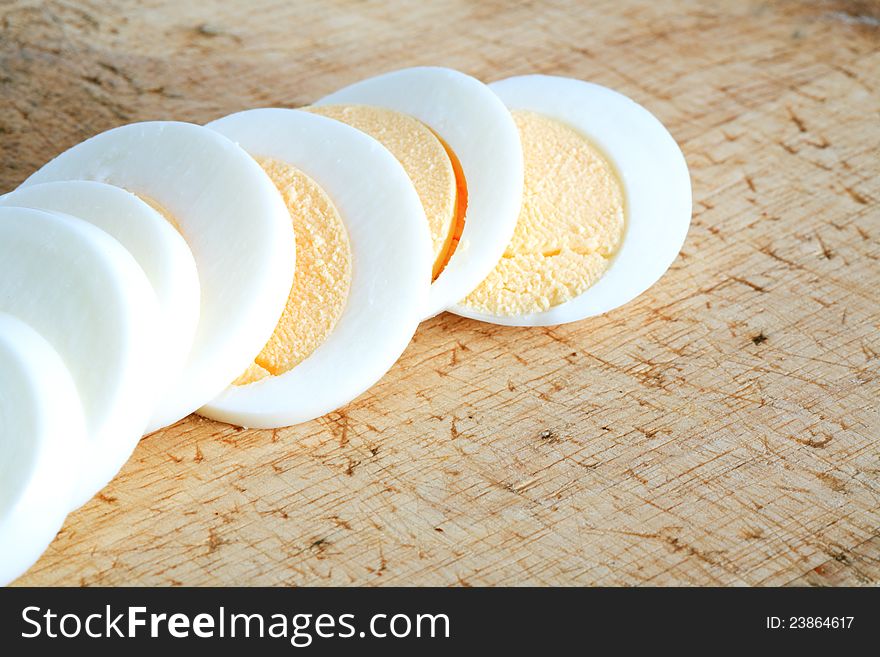 Sliced hard boiled egg on wooden surface. Sliced hard boiled egg on wooden surface