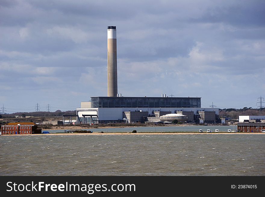 A coastal electricity generating power station against a dark cloudy sky. A coastal electricity generating power station against a dark cloudy sky