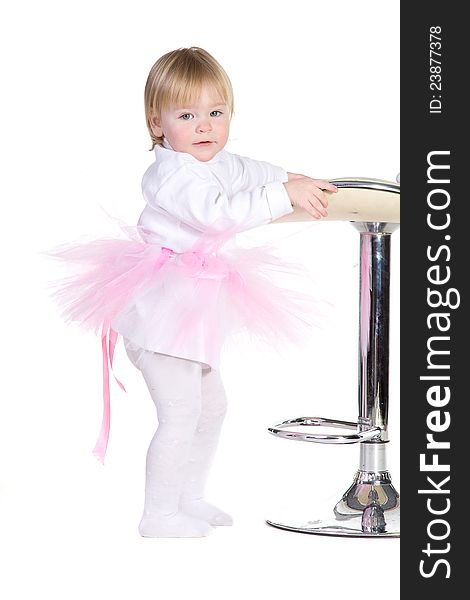 A little girl in a pink tutu standing near bar stool