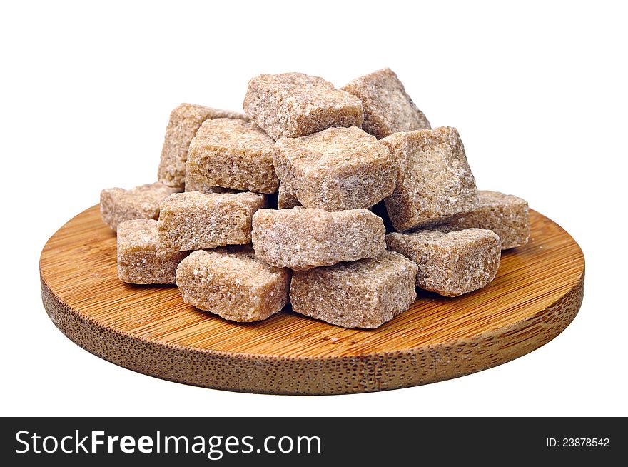 Cubes of brown cane sugar on a wooden board isolated on a white background