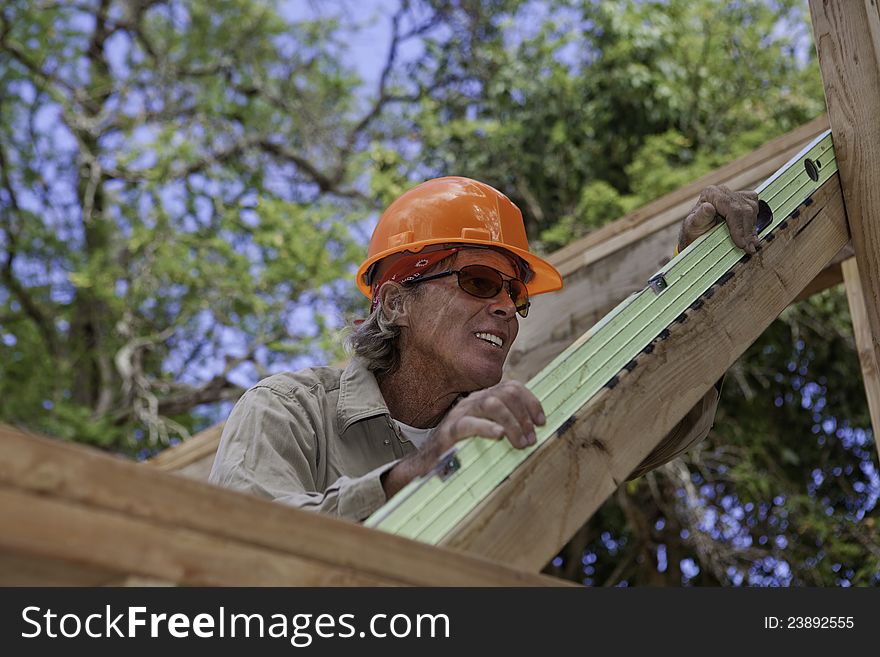 Senior male construction worker building a new house, using a level