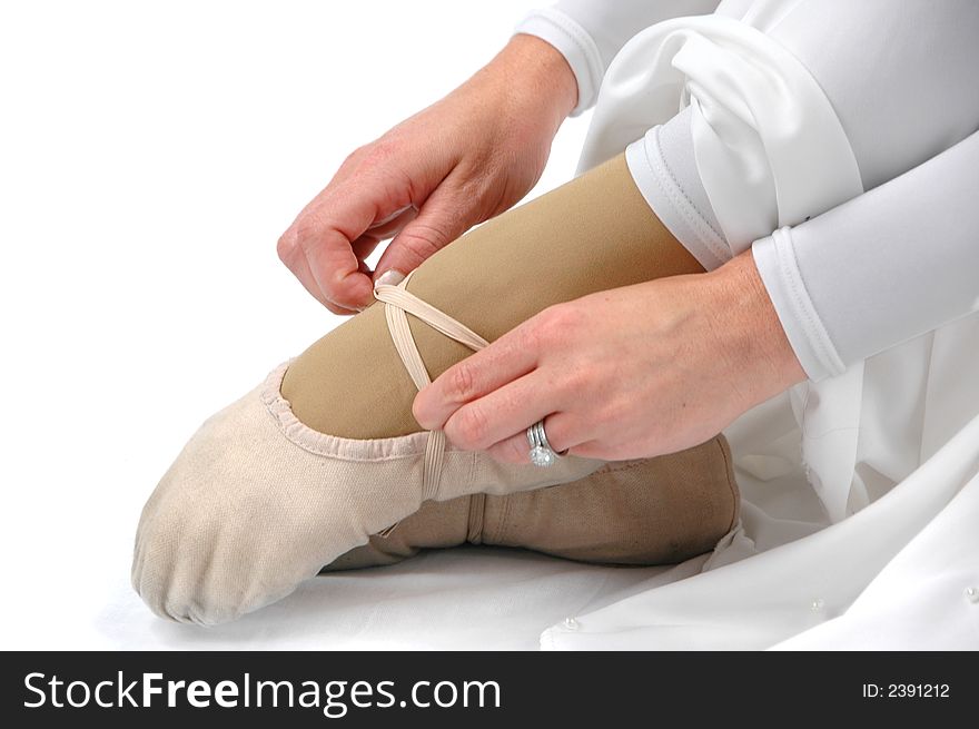 Ballerina tying her shoe against a white background