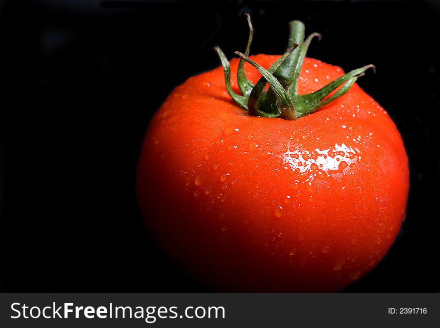 Vine ripe red tomato on a black background. Vine ripe red tomato on a black background