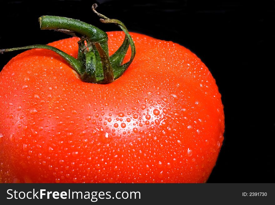 Delicious vine ripe red tomato on a black background. Delicious vine ripe red tomato on a black background