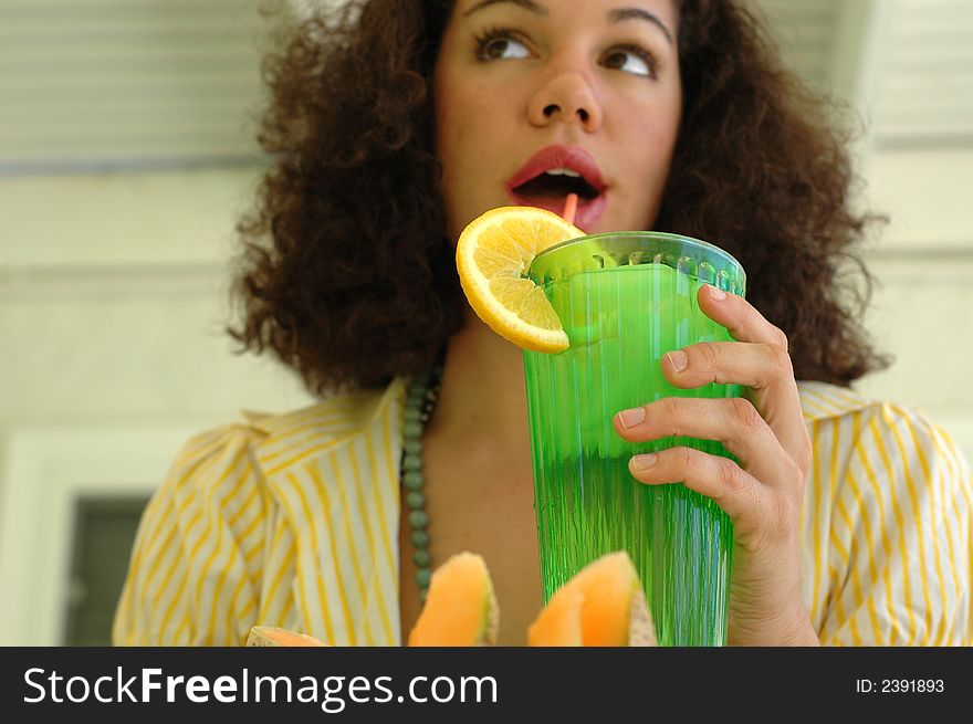 Attractive young woman drinking lemonade on a hot sumer day; seective focus on the hand and the glass