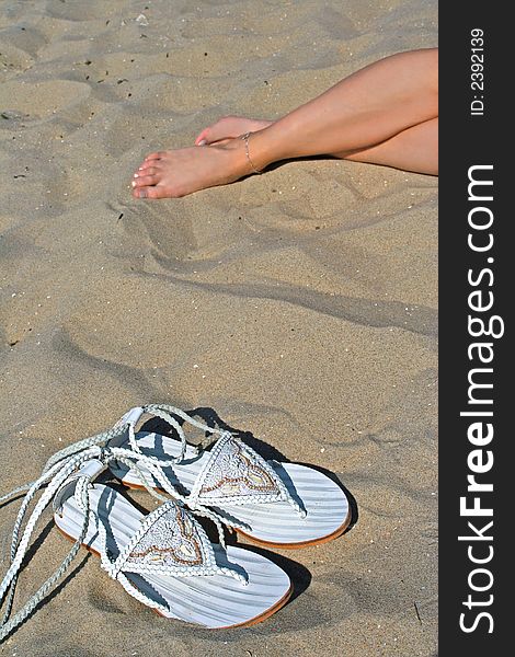Vacation time on beach with fashion slippers and women legs as background