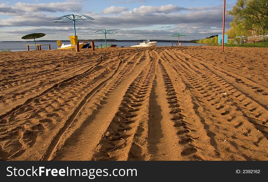 A photo of a sand beach with boats. A photo of a sand beach with boats