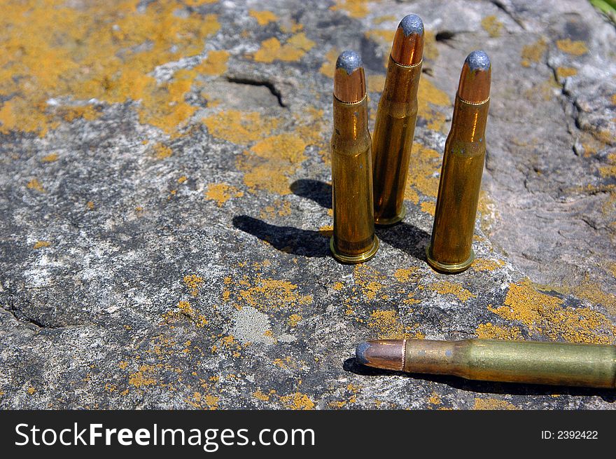 A small group of bullets sitting on an old chunk of sandstone.