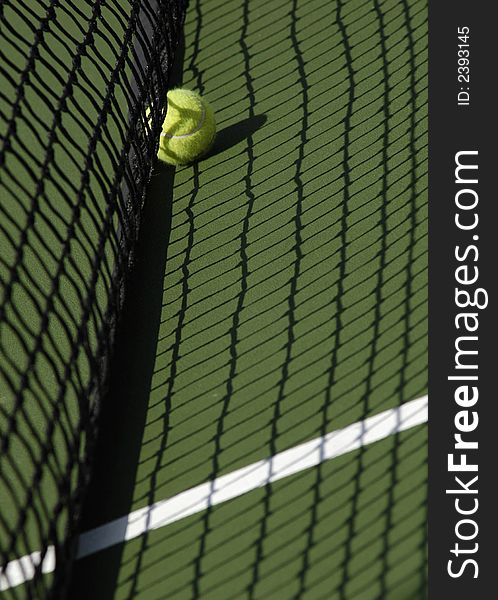 A lone tennis ball sitting a tennis court. A lone tennis ball sitting a tennis court.