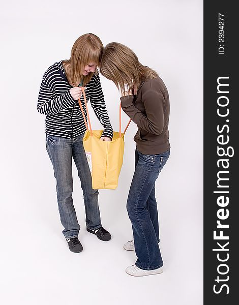 Teen girls are looking for anything in a yellow bag. Teen girls are looking for anything in a yellow bag