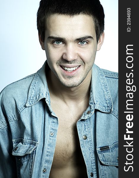 Smiling attractive yyoung man in blue jeans shirt on white background. Smiling attractive yyoung man in blue jeans shirt on white background