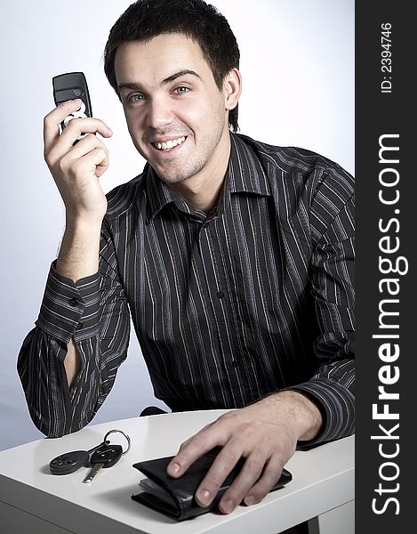 Smiling young man with car keys and wallet speaking phone. Smiling young man with car keys and wallet speaking phone