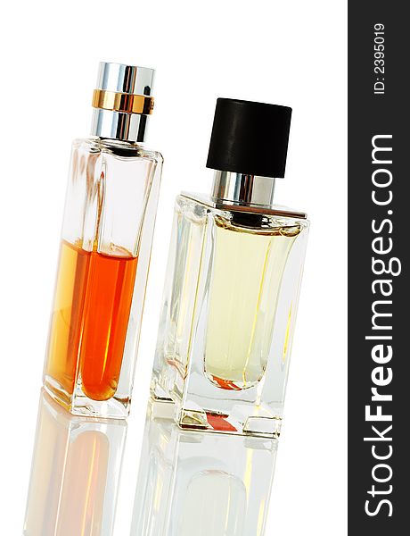 Two elegant perfume bottles standing on reflective surface.