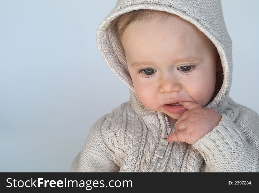 Image of cute baby wearing a hooded sweater, sitting in front of a white background. Image of cute baby wearing a hooded sweater, sitting in front of a white background