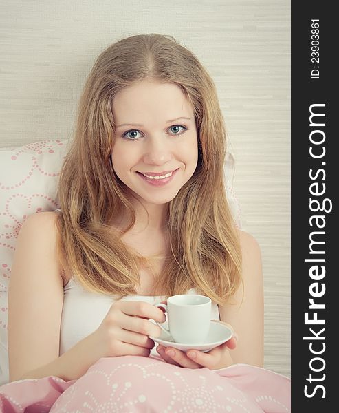 Beautiful young woman with a cup of morning coffee in bed. Beautiful young woman with a cup of morning coffee in bed